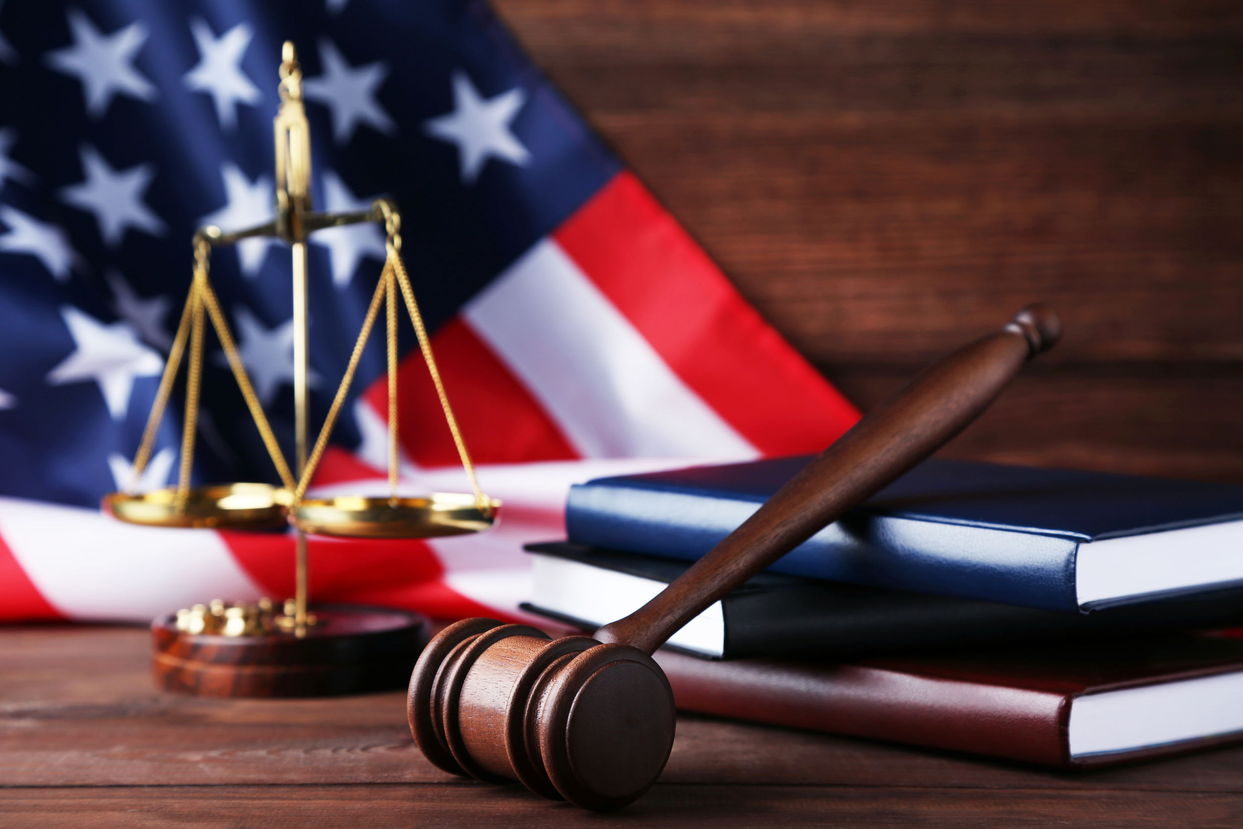 Judge gavel with scales, books and american flag on wooden table